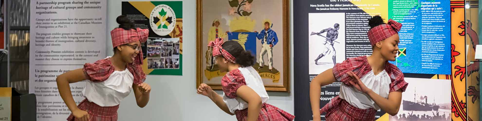 Three people in costume dance in front of the exhibition.