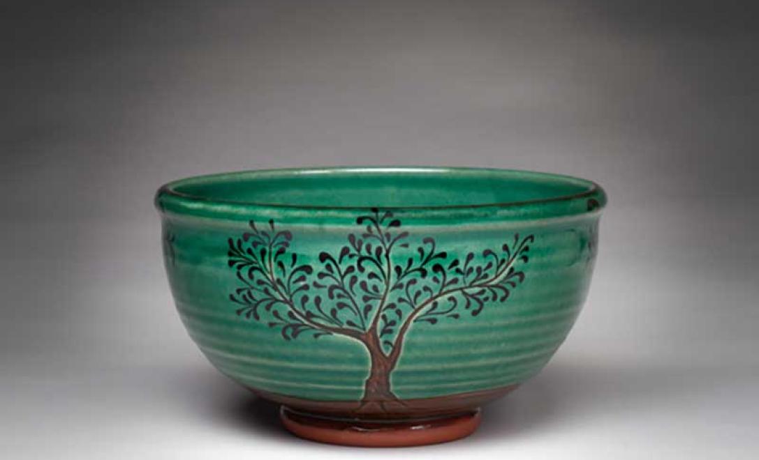 Overhead view of several newly made pottery bowls sit side by side, all beautifully glazed in green.