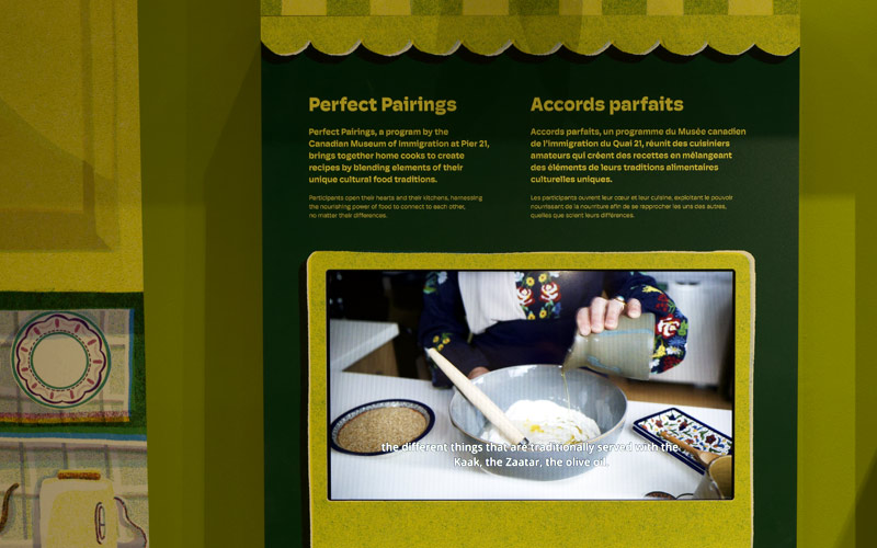 A green wall featuring a video of a woman cooking, with text explaining the Museum’s Perfect Pairings program.