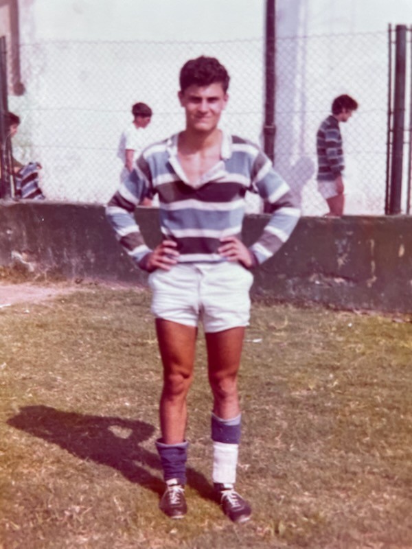 An old photo of a young man posing in a blue and grey striped rugby jersey.