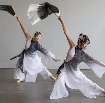 An Indian woman in a sari serves a curry to a young woman of European descent at Museum event.