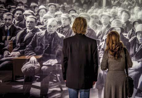 A floor to ceiling photograph of immigrants waiting in the Assembly Hall.