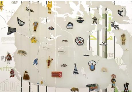 A large map of Turtle Island on a glass wall with Indigenous glass art throughout.