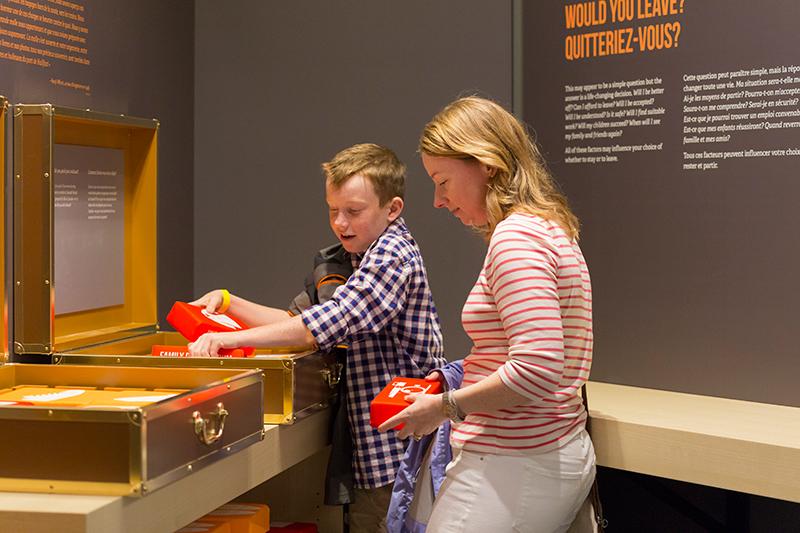 A woman and young boy stand next to an interactive display at the museum.