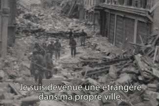 Soldiers walk through a rubble-filled street.