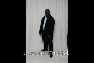 A nice-looking young man stands in front of a cloth backdrop.