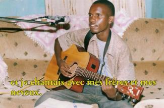 A young man plays guitar and sings into a microphone.