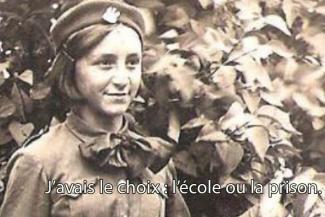 A young girl in uniform stands and smiles.