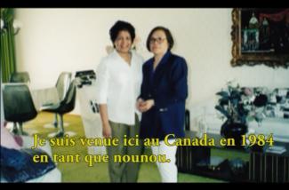 Two women stand in a living room with green carpeting.