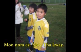 Two young boys wearing soccer jerseys are standing on a field.