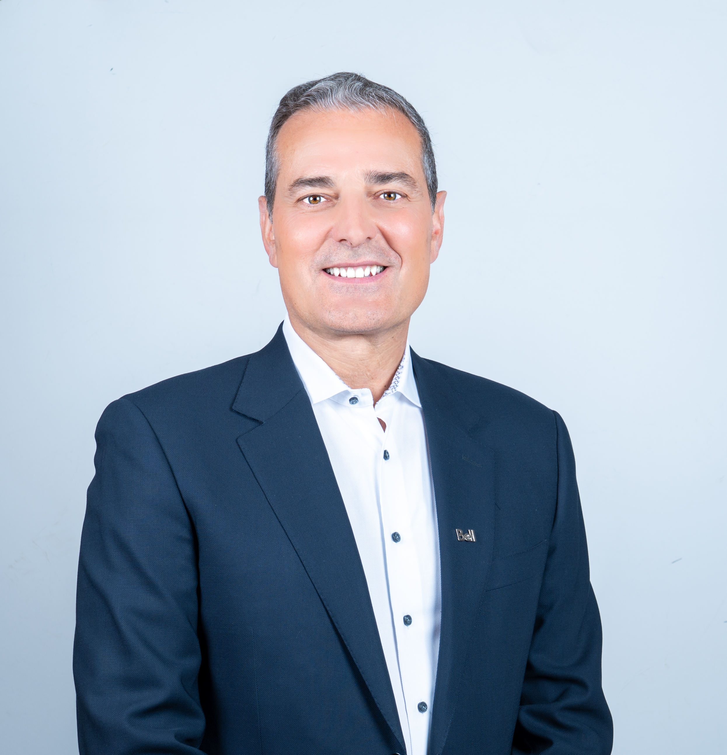 A portrait of Mirko Bibic wearing a suit and smiling.