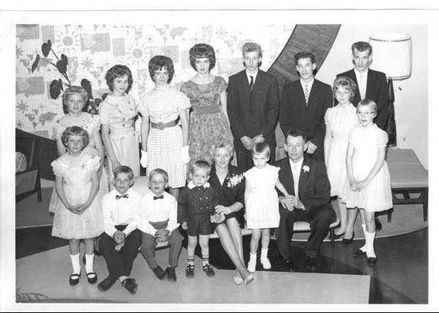 Well dressed group of family members sitting and standing for photo.
