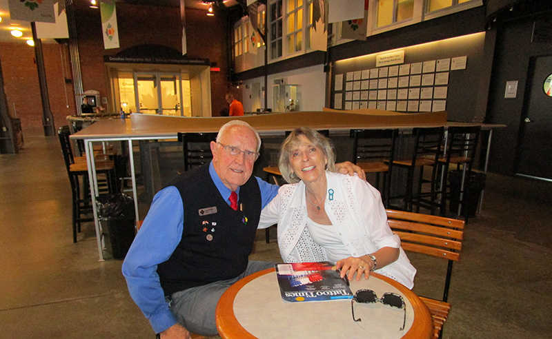 A man and woman are sitting on a bench at Pier 21.
