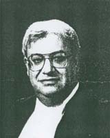 Black and white photo of young man, he is wearing glasses.