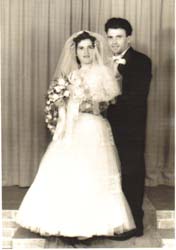 Portrait of bride and groom on wedding day, posing in front of curtained area.