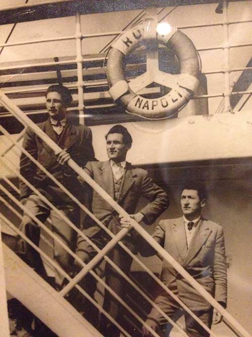 Sepia image of three men standing on different levels of a staircase