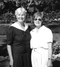 Ausma in white standing outside with female friend.