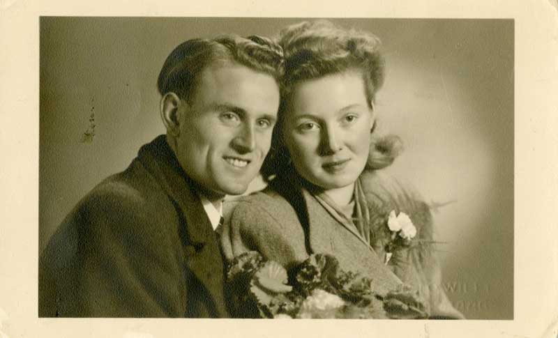 A man and woman look off to the side of the camera, both smiling very broadly.