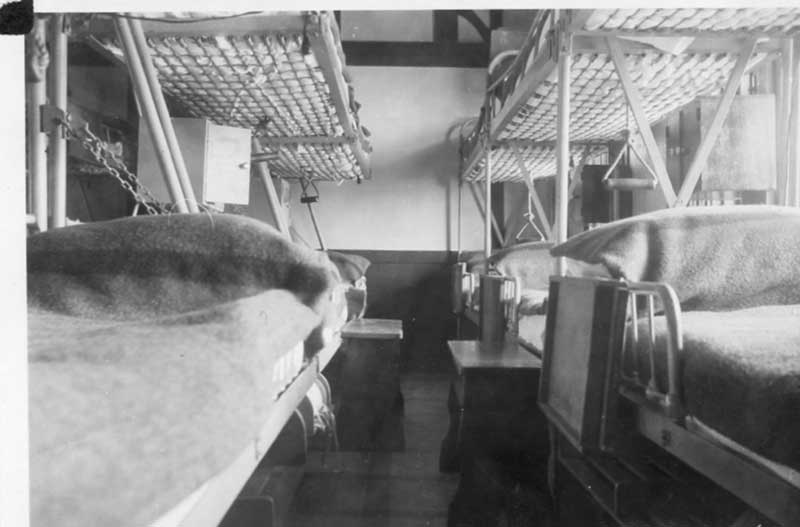 Miltary bunk beds with a side table and a jug on it.