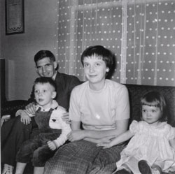 Young man and woman sitting on a couch with a little boy and a girl.