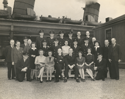 Several immigration officers sitting or standing in front of a boat.