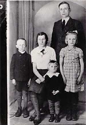 A young family sit for a portrait, their faces are very serious.