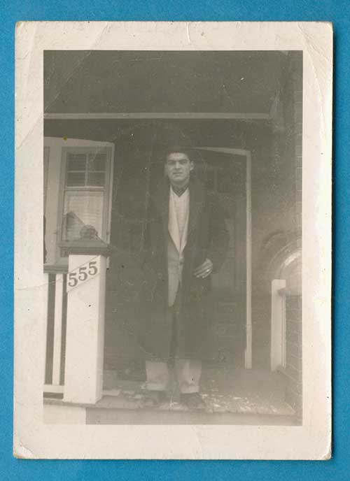 Young man standing in a porch withd house number 555 on his right side.