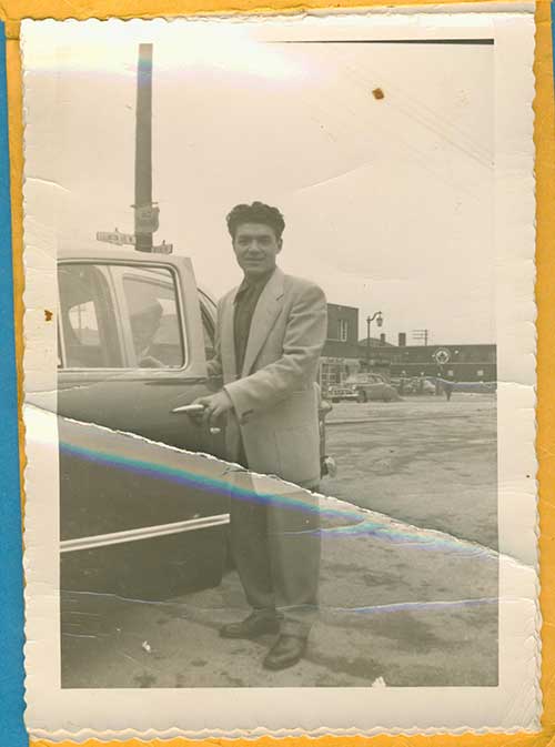 Well-dressed young man is opening a car door.