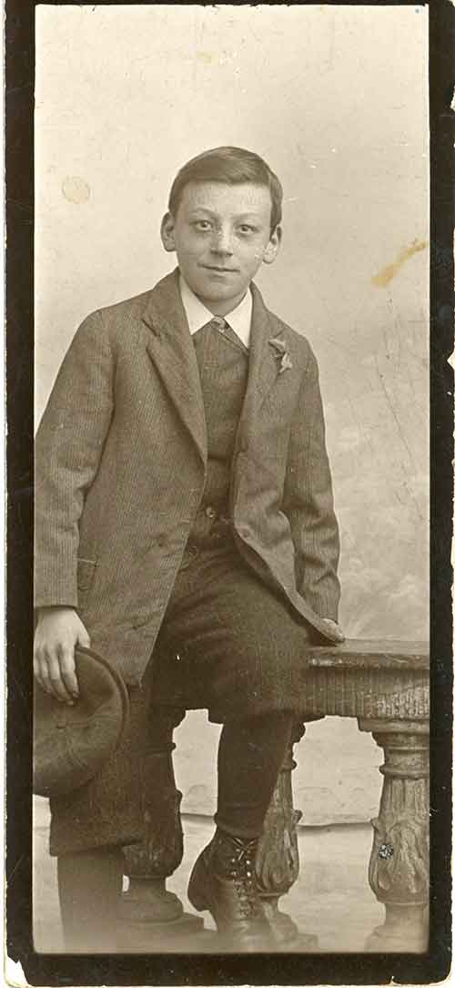 A young man is half-sitting on a stool, wearing the clothing of the time.