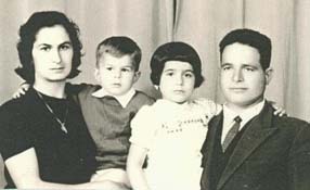 Family portrait of a mother and father, each holding a small child.