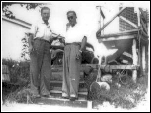 Two men standing on steps in front of house.