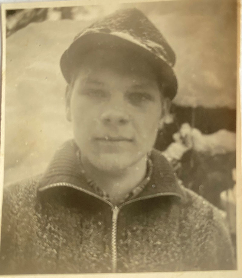 Young man stands and snow is falling on him.