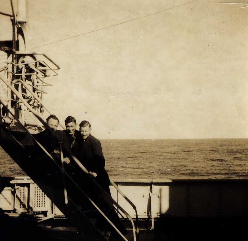 Three young men stand on a flight of stairs.