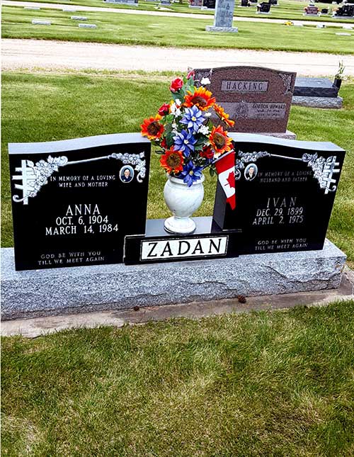 Two tombstones with a vase of flowers between them.