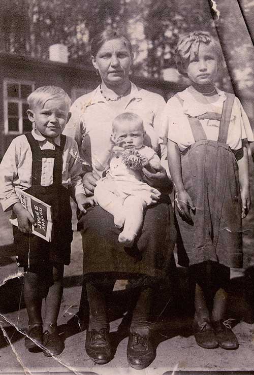 Archived photo of young woman seated with a baby in her lap and two small children standing next to her.