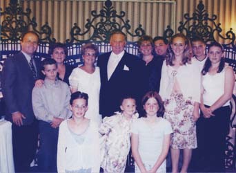 Recent coloured family photo with children in front and adults in back.