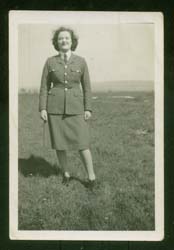 Young Joan in military uniform, standing in the distance outside.