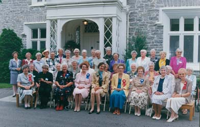 Recent colour photograph of a group of women sitting and standing outside a building.