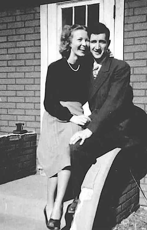 A young laughing woman sits on the lap of a young man.