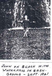 John on beach with waterfall in background.