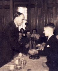Young boy shaking the hand of an older gentleman with other people clapping.