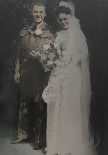 Archival portrait of a bride and groom on their wedding day, the bride holds a beautiful pink and white flower bouquet.