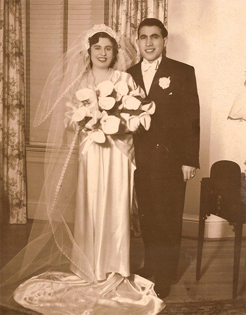 A bride holding flowers stands with the groom for a photo.