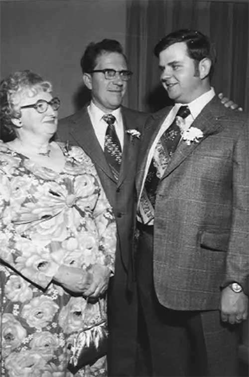 Mother and father look proudly at their son on his wedding day.