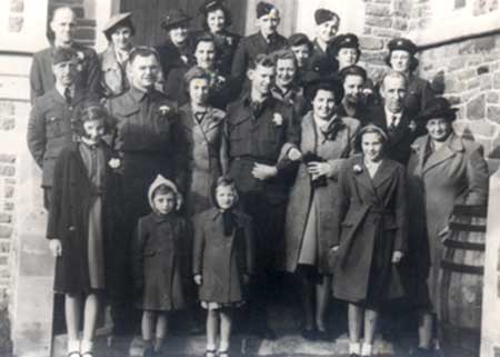 Group of people standing in front of a building, some of them are wearing uniforms.