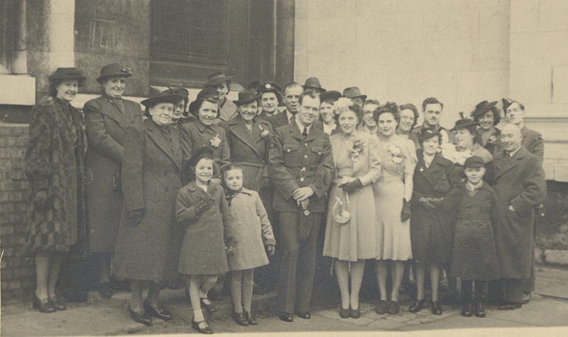 Grace and Arnold’s wedding picture, with their friends and family standing with them.