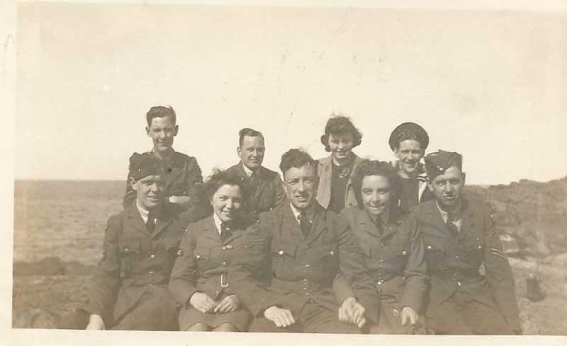 A group of young men and women wearing military uniforms pose for the camera.