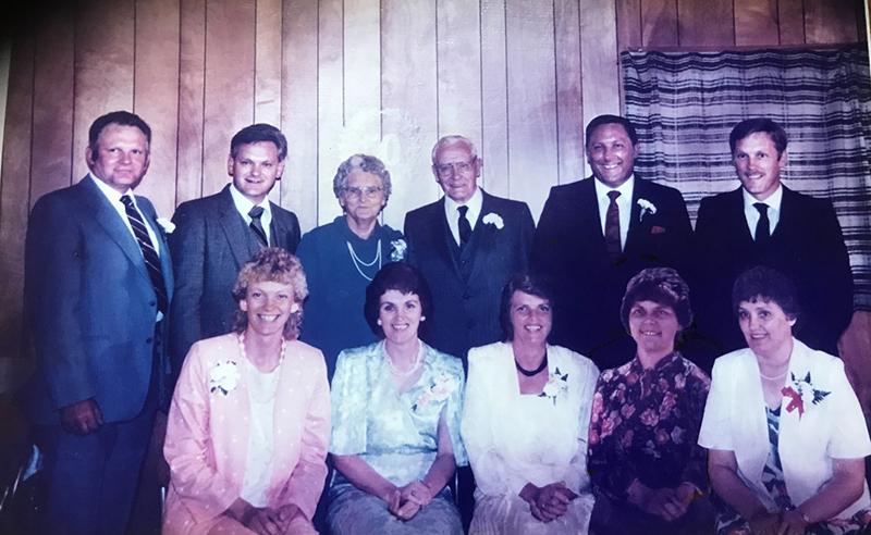 Nine adult siblings pose for a photo with their parents.