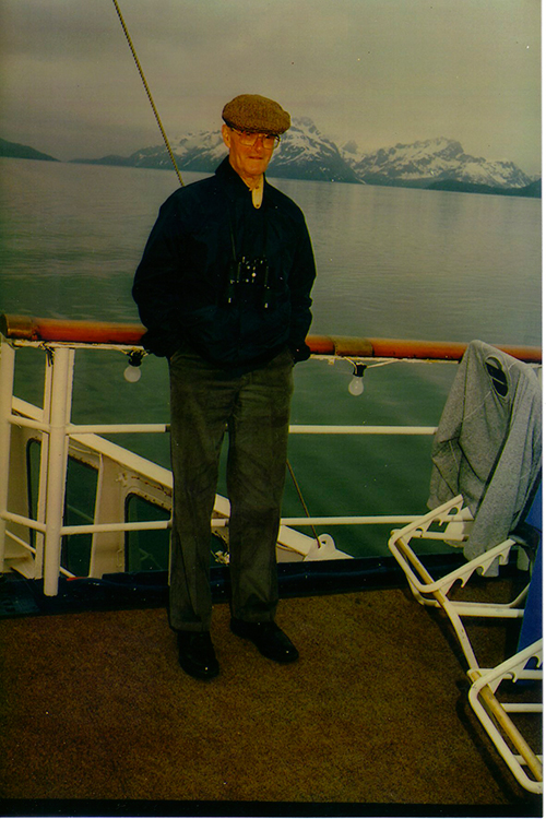 Well-dressed handsome man standing on the ship's deck.