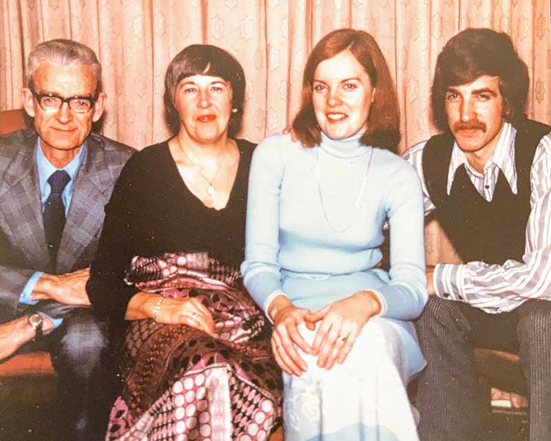 Four members of a family are sitting and having their photograph taken.